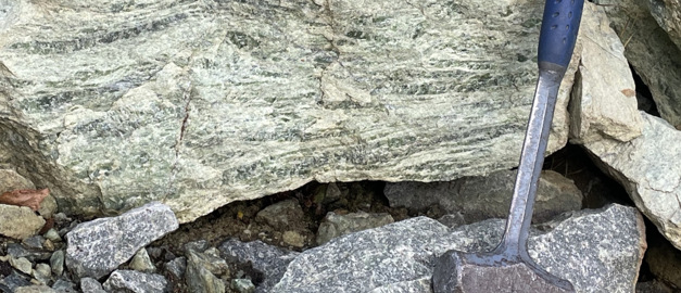  Sten med brottyta och en geologhammare