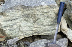  Sten med brottyta och en geologhammare