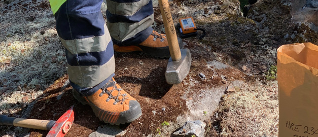 The picture show a geologist feet on the ground with tools laying on the ground. The picture show a geologist feet on the ground with tools laying on the ground.