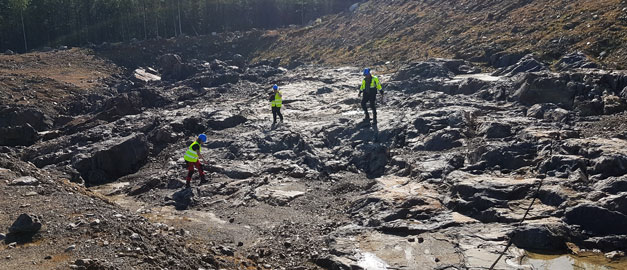 Tre personer med varselvästar gräver i marken. Tre personer med varselvästar gräver i marken.