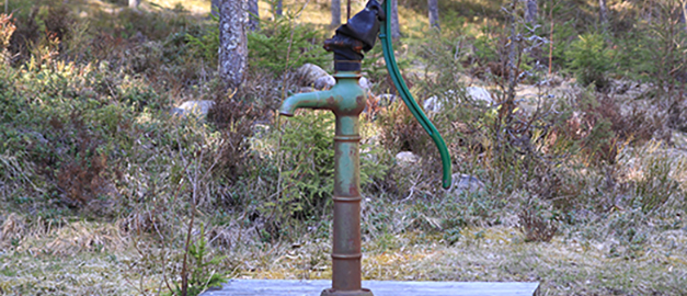 En dricksvattenbrunn med handpump. 