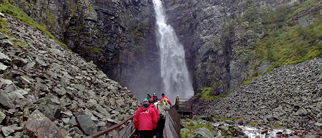 Foto av en grupp turister som går mot ett vattenfall.