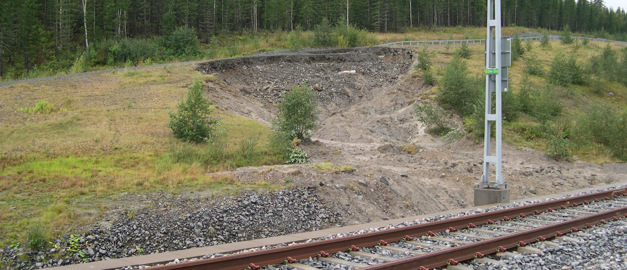 Foto av ett skred nära ett järnvägsspår.