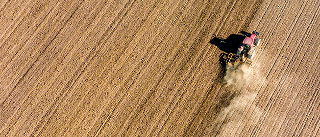 Bild på traktor som kör på åker.