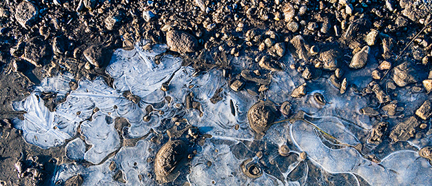 Bild på fruset vatten och stenar.