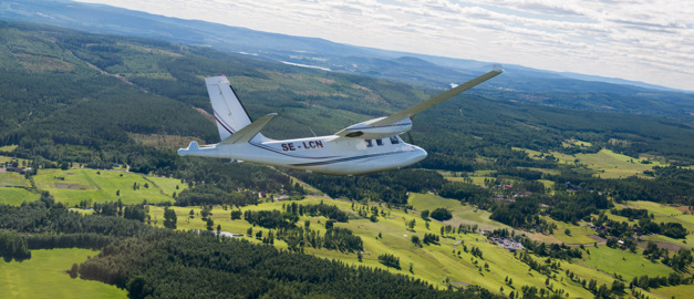 Flygplan som flyger över skog och sjö.