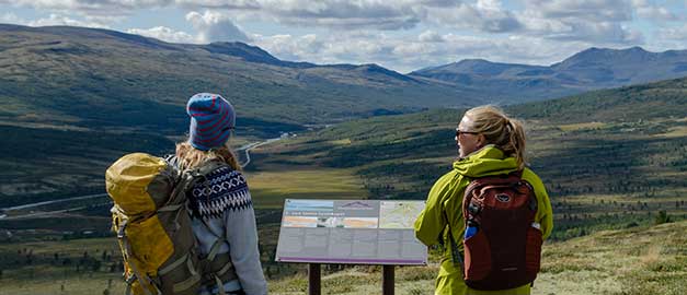 Två personer klädda för fjällvandring. I bakgrunden syns fjäll. Foto. Två personer klädda för fjällvandring. I bakgrunden syns fjäll. Foto.