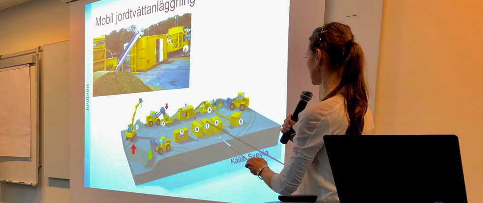 En person står och pratar till en powerpoint-bild. Foto.